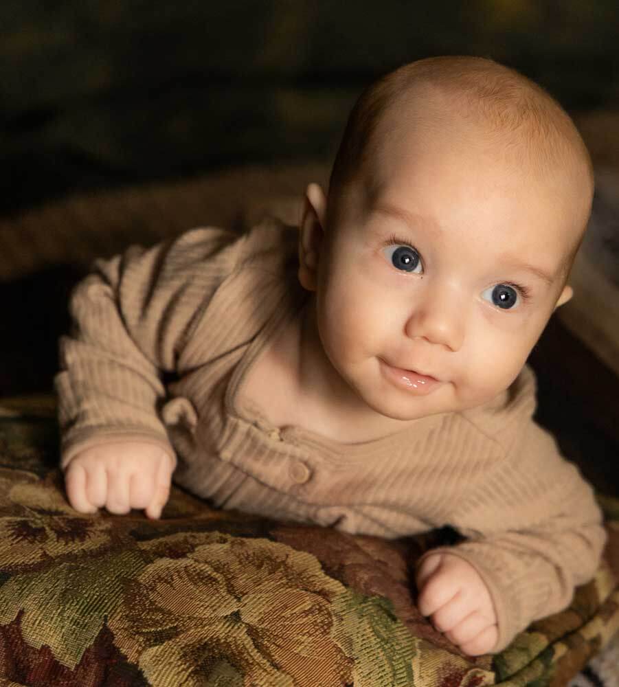Newborn baby boy with big blue eyes soft glow